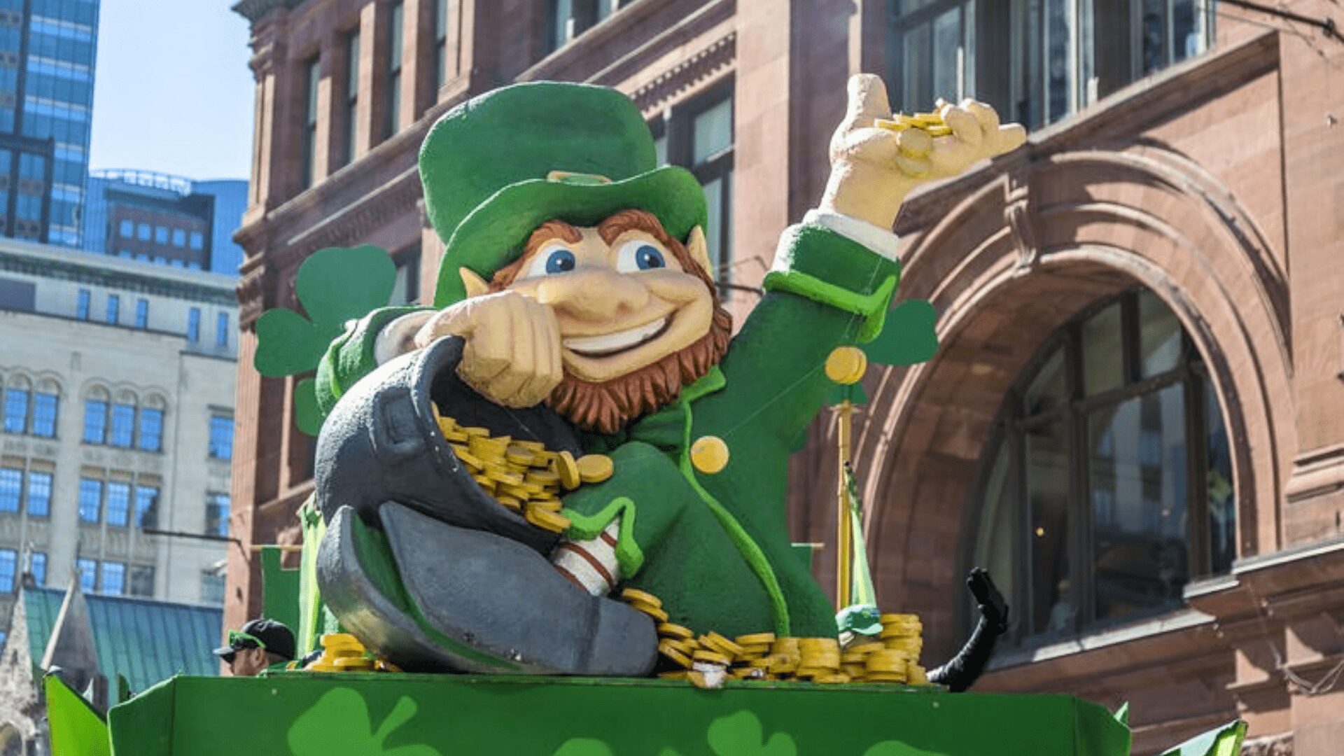 Sculpture de leprechaun au défilé de la Saint-Patrick de Montréal, entourée de décorations vertes et de pièces dorées
