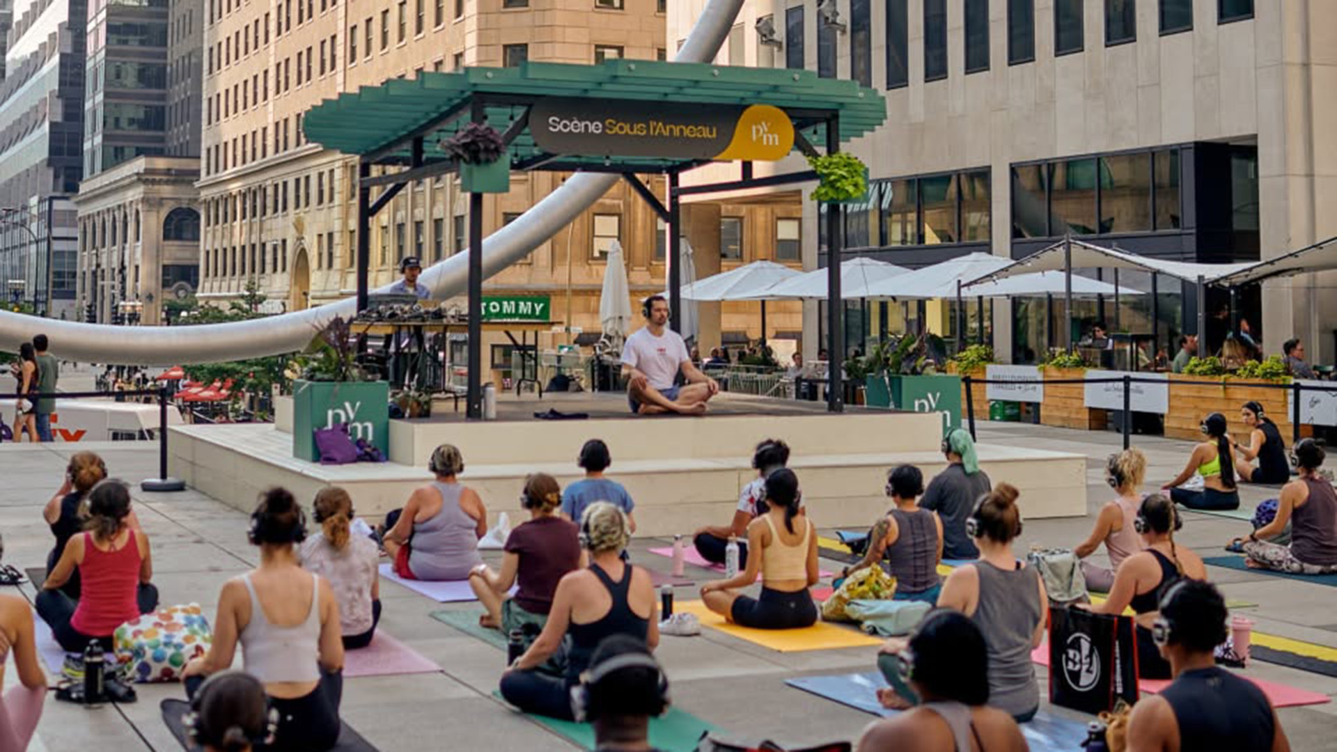 Séance de yoga immersif YogaTribes sous l’Anneau à l’Esplanade PVM au centre-ville de Montréal.
