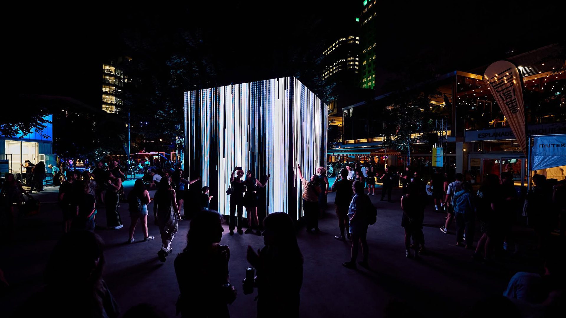 Installation lumineuse immersive au cœur du Festival MUTEK, entourée de visiteurs en soirée.